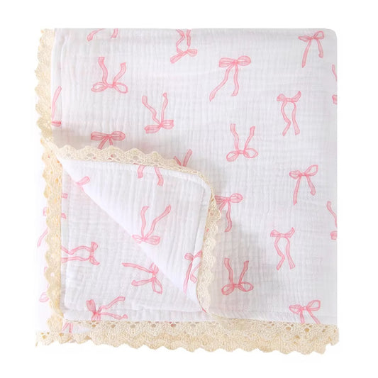 White cotton muslin baby blanket with pink bow print and delicate cream lace edging