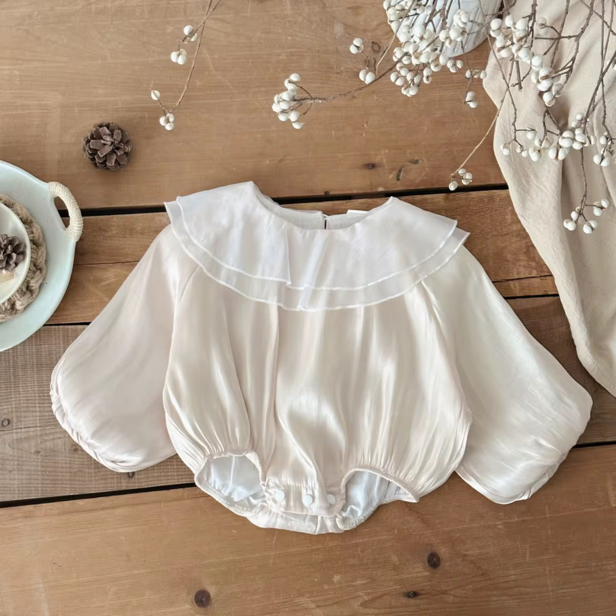 Infant romper in white with layered frill neckline and elastic cuffs