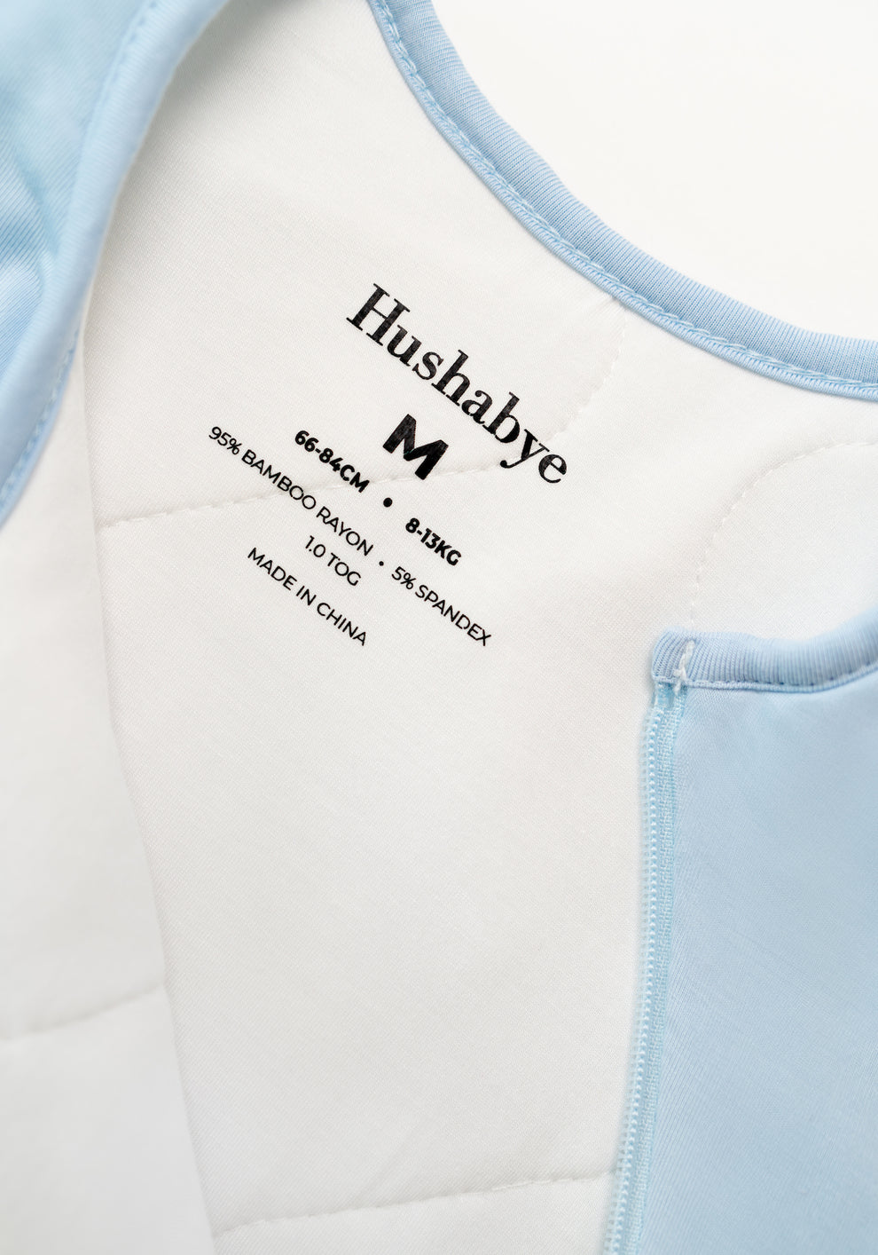 Powder blue padded baby sleep sack with sleeveless design, side zip opening, and soft cushioned bottom on a white background.