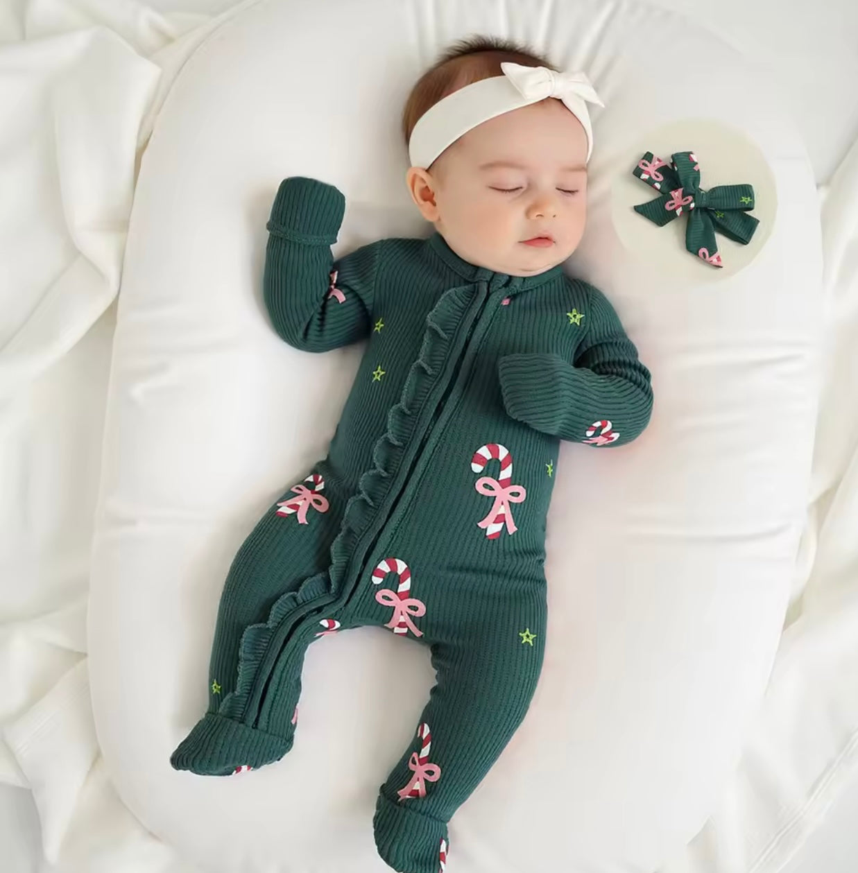 Infant girl wearing cozy ribbed romper with candy cane bows and matching hair accessory.
