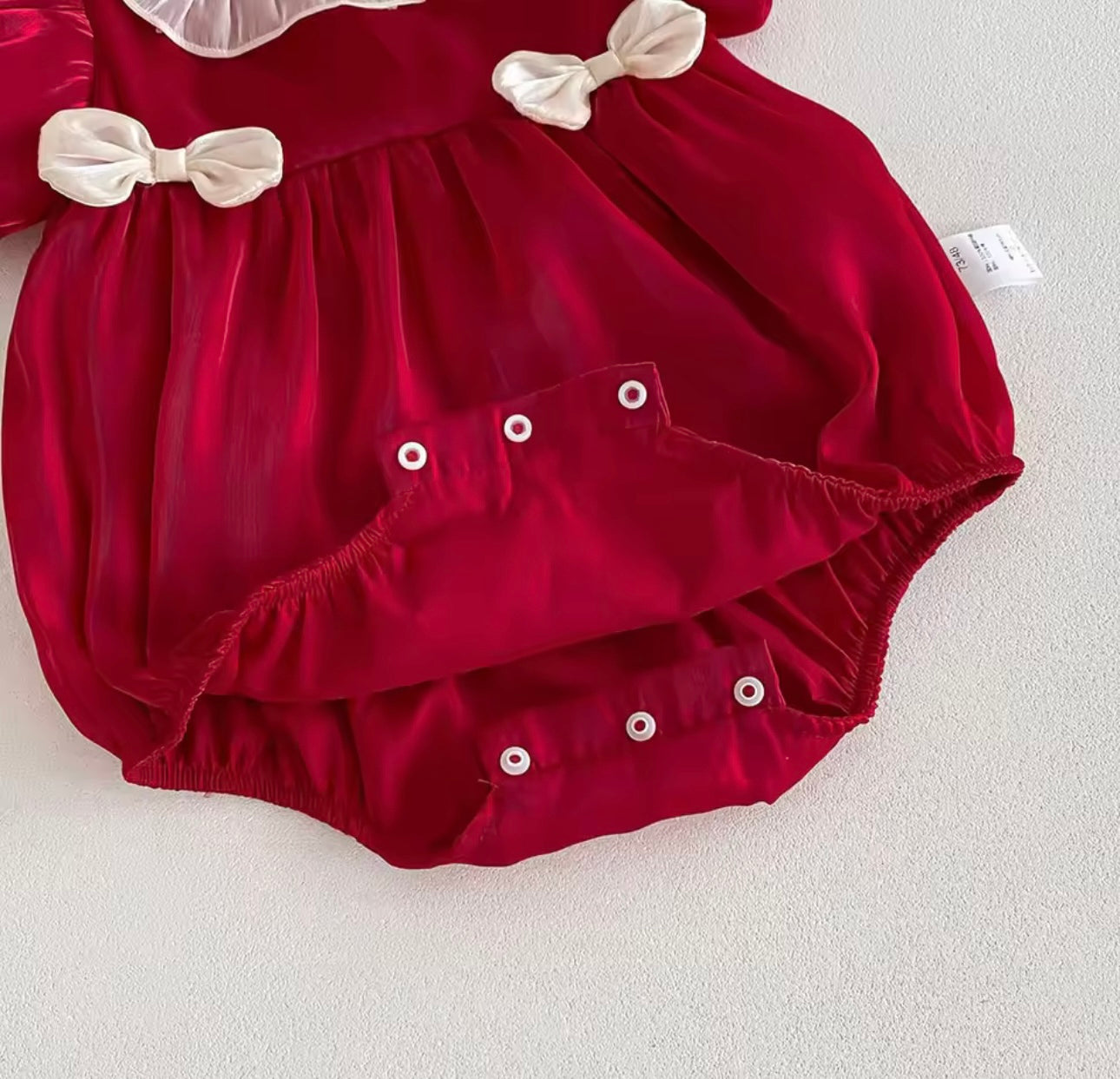 Infant holiday romper in bright red with puff sleeves and white accents.