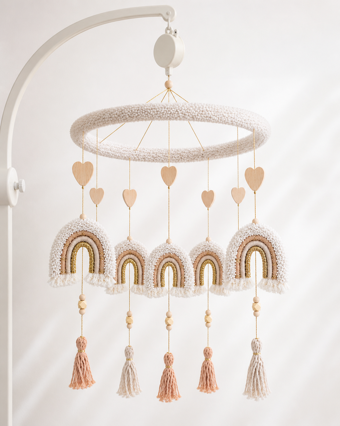     Neutral rainbow baby mobile with ivory boucle ring, wooden hearts, tassels, and soft boho nursery decor hanging on white background.