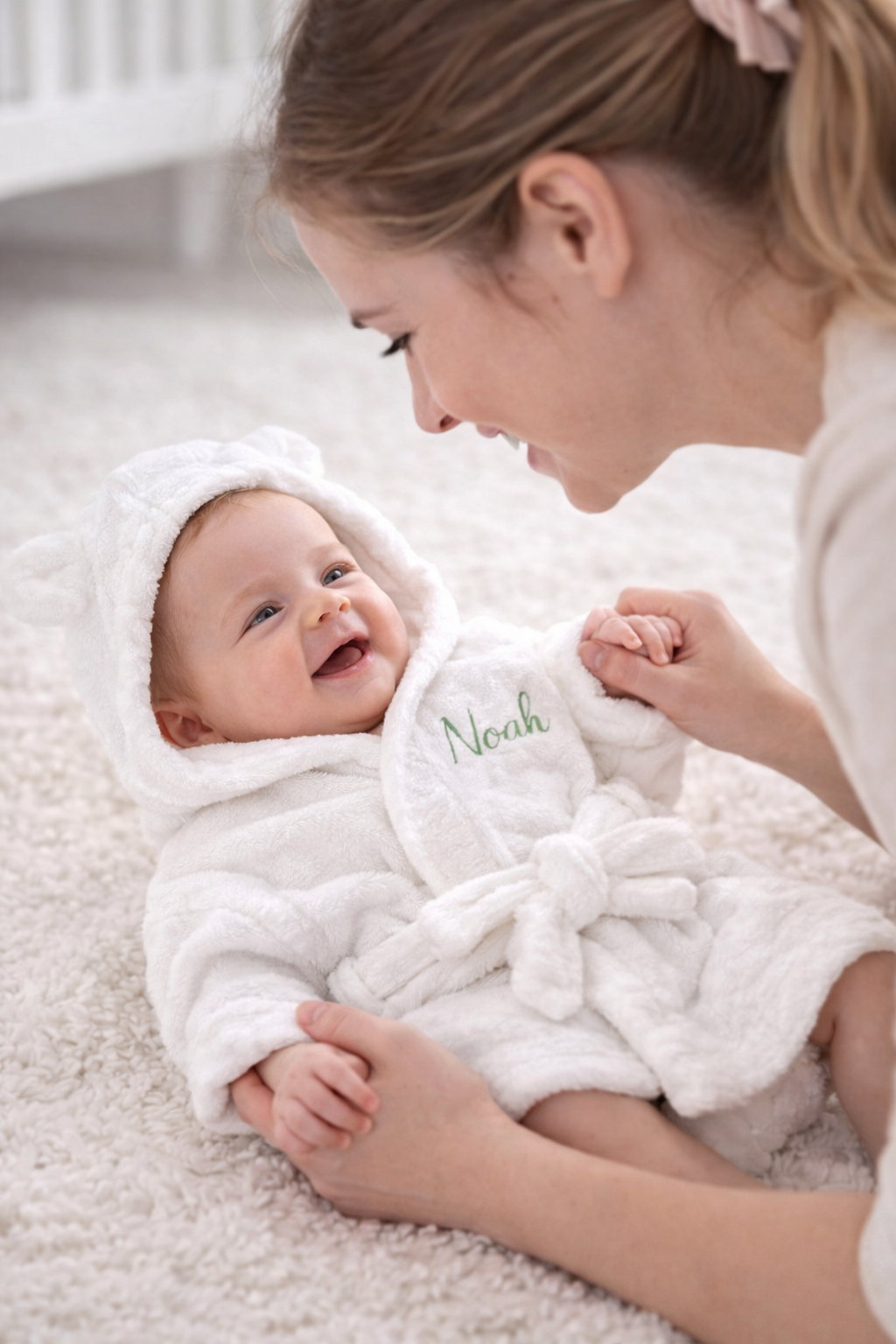 Personalised hooded baby bathrobe styled with nursery items — perfect baby shower and Aqiqah gift in the UAE
