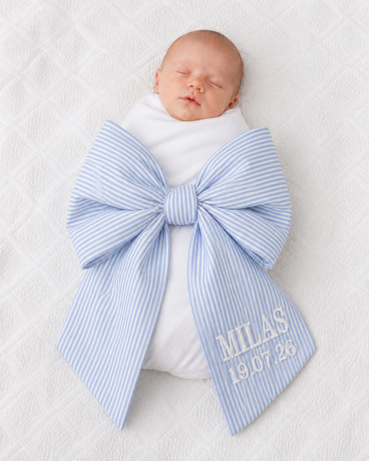 Newborn baby wrapped in personalised blue stripe bow sash with custom embroidery — Maxims Baby Store Dubai UAE