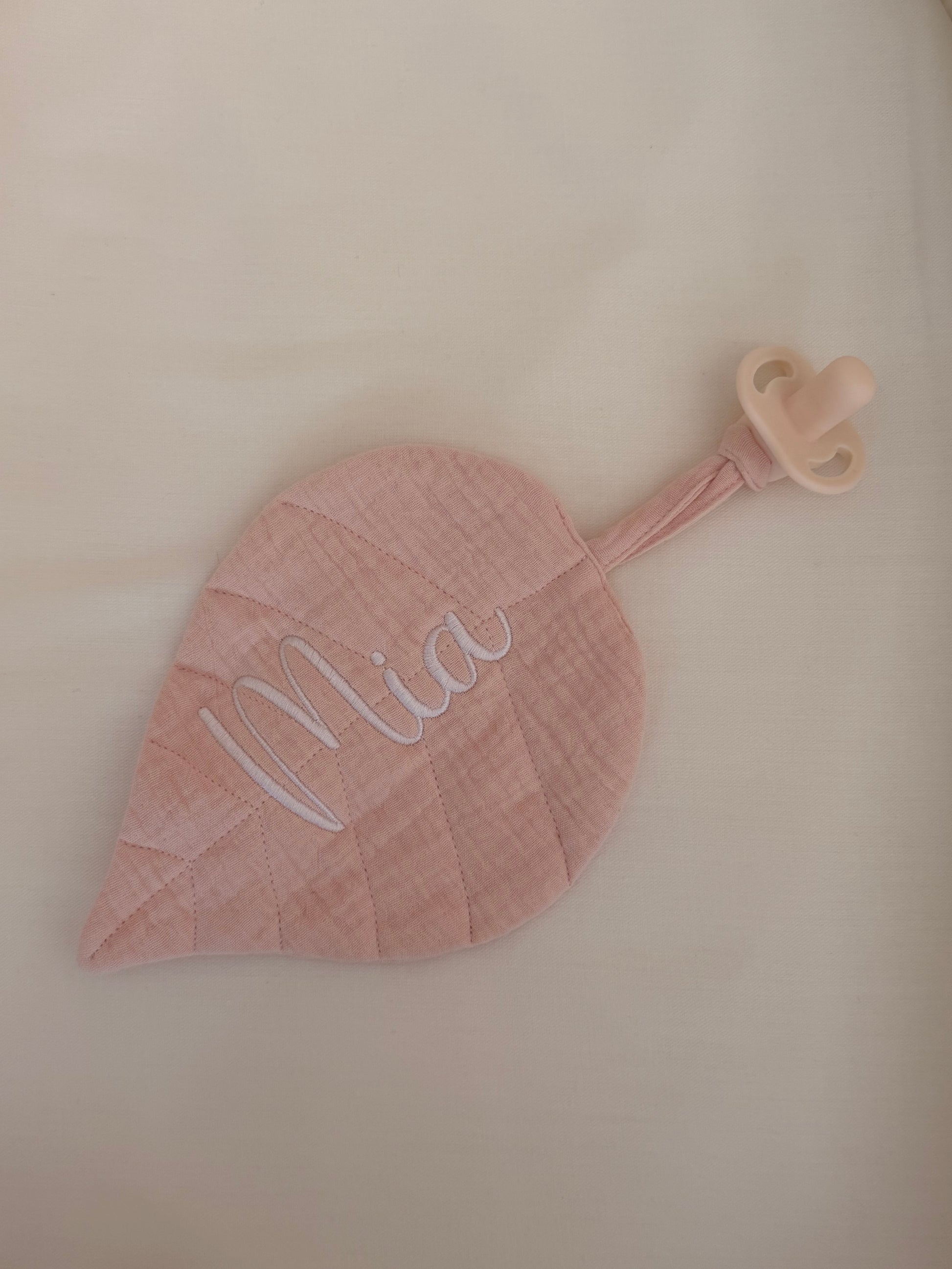 Soft pink muslin pacifier holder personalised with baby’s name, a sweet baby girl gift