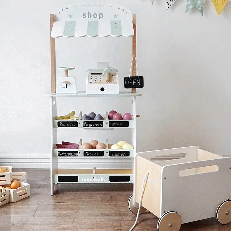 Wooden Montessori play shop with cash register, OPEN sign and pull-along wooden shopping cart, perfect for toddler role play.